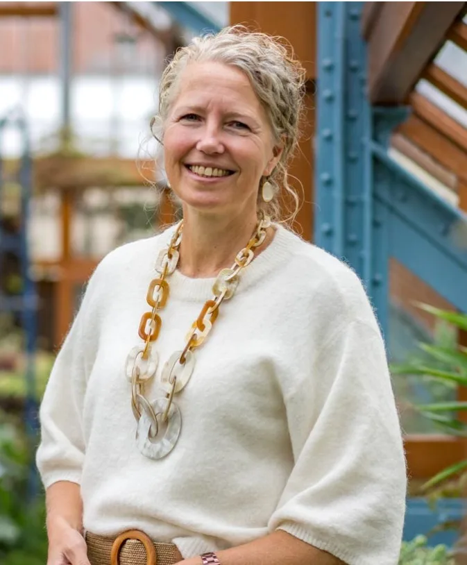 Margje Kooiker, orthopedagoog, glimlachend in een groene tuin